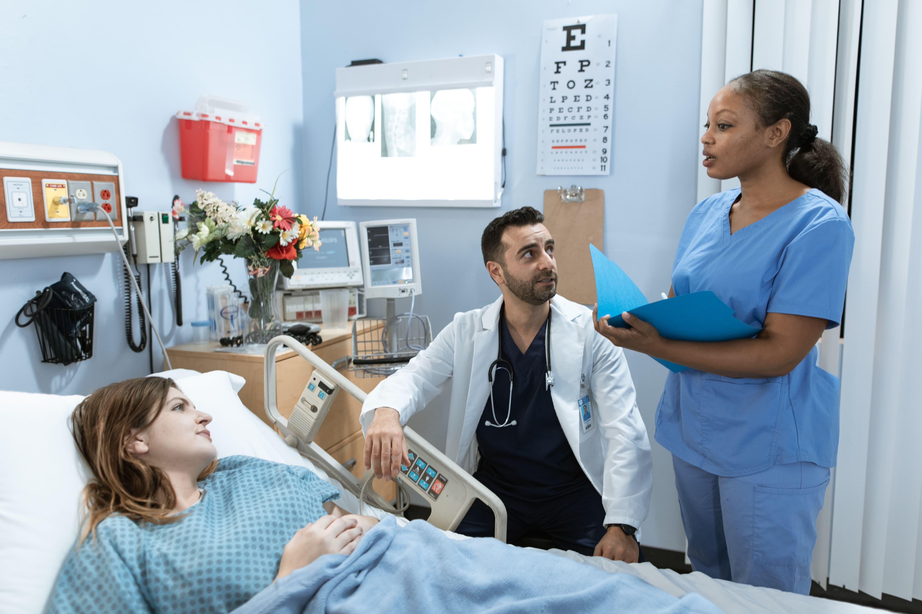 A nurse and doctor discussing patient treatment in a hospital room